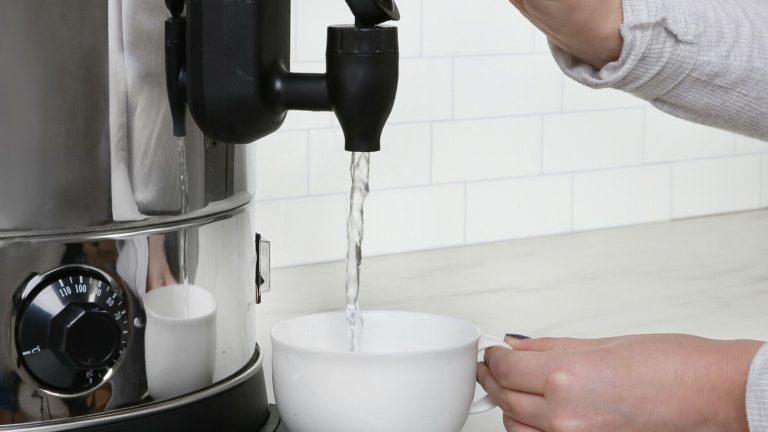Commercial water boiler pouring hot water into a cup