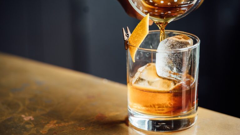 Pouring whiskey into a glass with ice from an ice cube maker