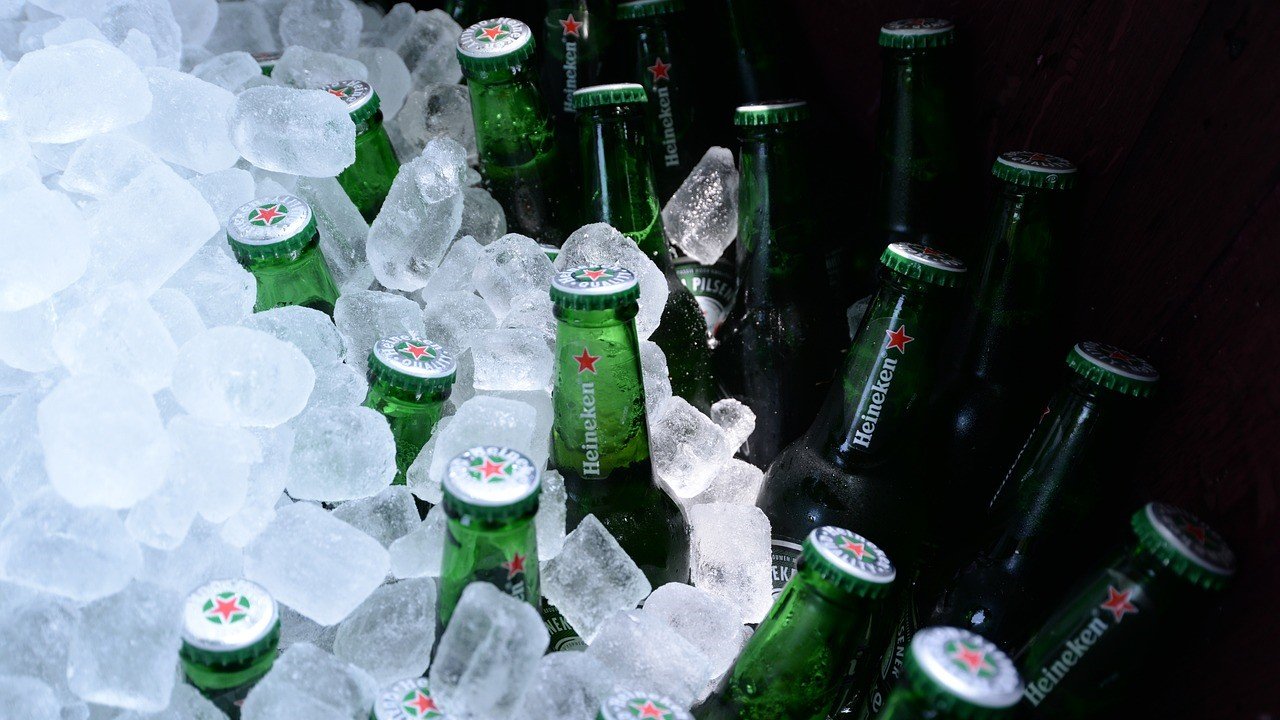 Ice cubes from ice machine around beer bottles