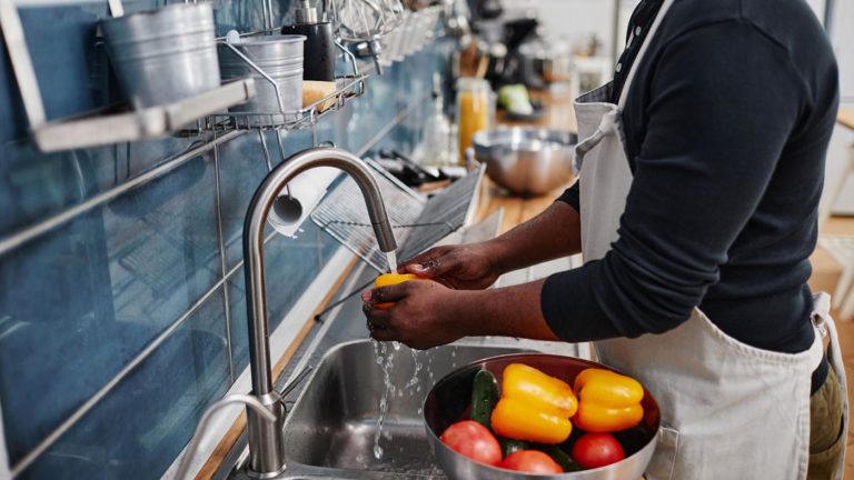 Cook washing produce at a stainless steel sink